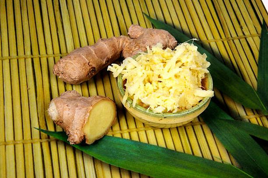 Two pieces of root ginger with a dish of grated ginger