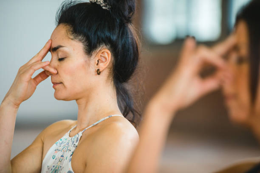 Two women practicing alternate nostril breathing (Nadi Shodhana) during a yoga or meditation session.