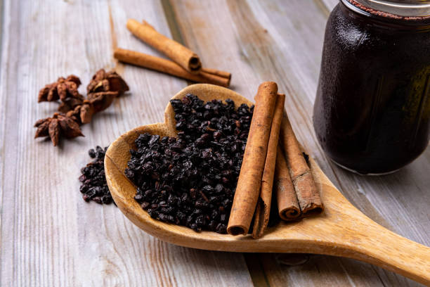 elderberries, cinnamon sticks, and star anise are spread around the jar