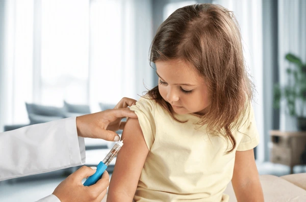Young girl receiving a vaccine shot in her upper arm from a healthcare professional