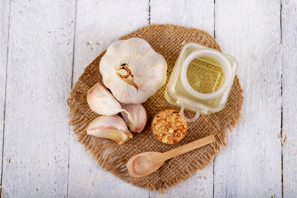 Garlic, oil, and powder on burlap over white wood.